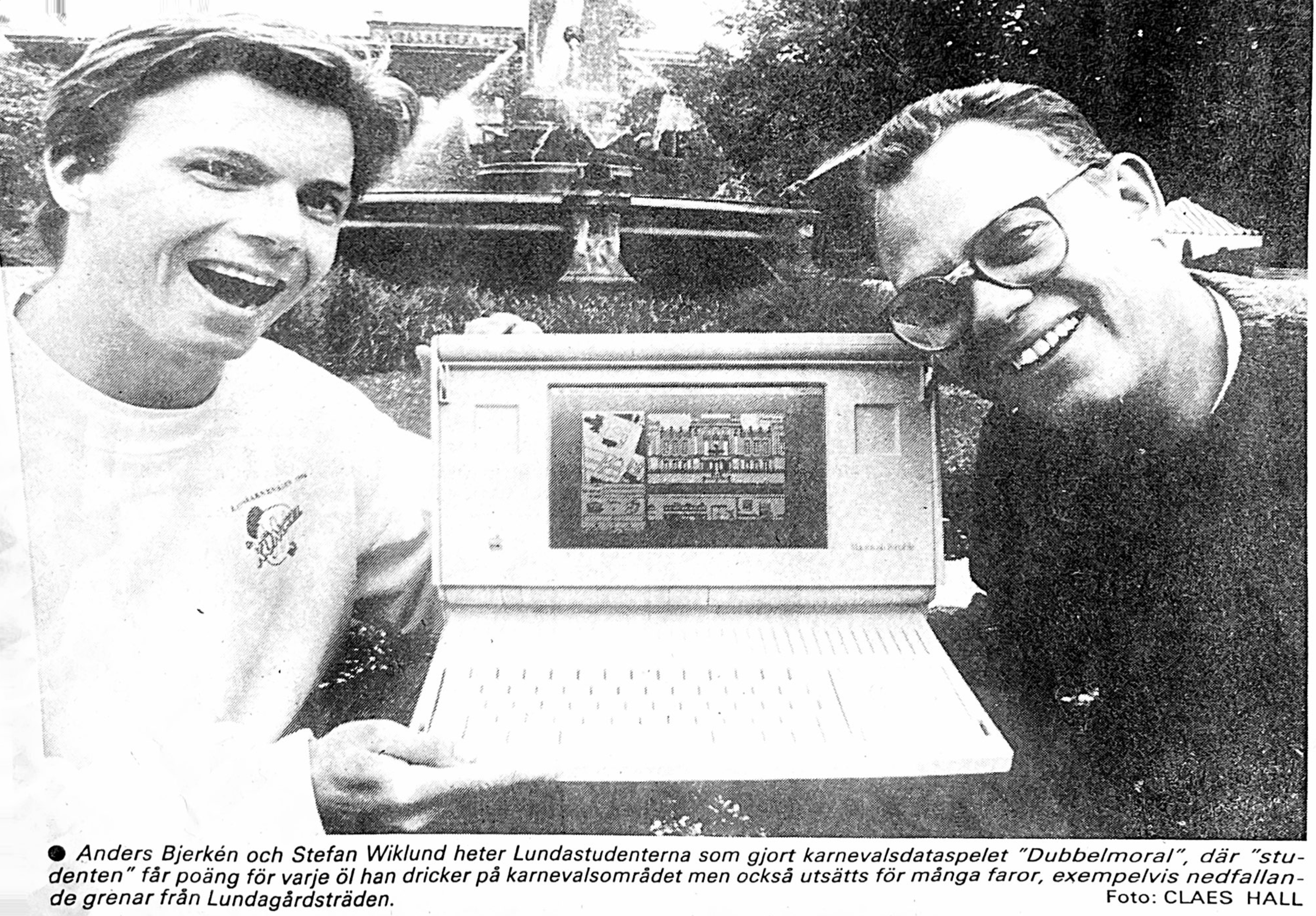 Anders Bjerkén och Stefan Wiklund visar upp Dubbelmoral! på en bärbar Macintosh under Lundakarnevalen 1990. Svartvitt tidningsfoto från Sydsvenskan.